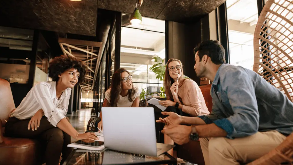 Diverse team collaborating in a modern office space, working with laptops and whiteboards, representing the dynamic and creative environment at Impact Digital.